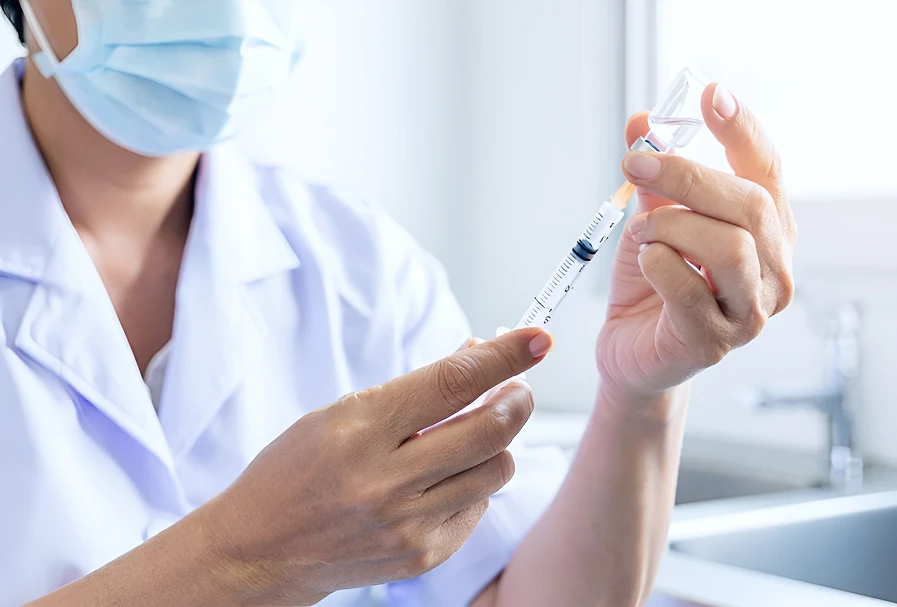 Врач в перчатке держит шприц